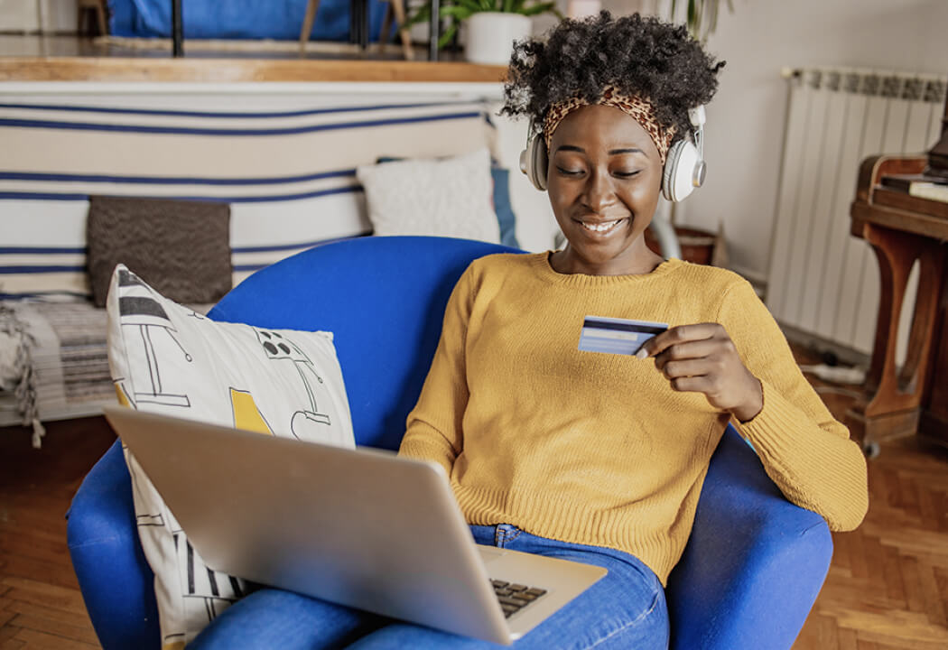 Young woman looking at a credit card and a laptop