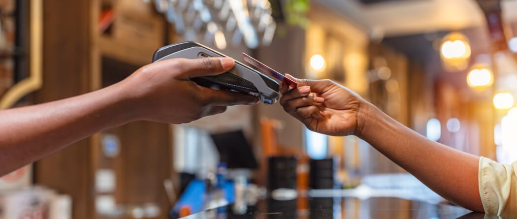 Two hands, one is holding a card reader and the other is holding a credit card