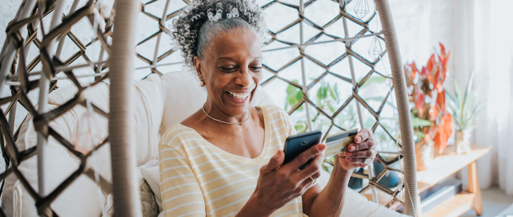 Older woman holding a credit card and a smartphone
