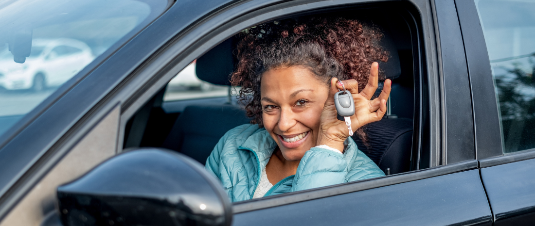 Woman in drivers seat of car, holding keys and smiling